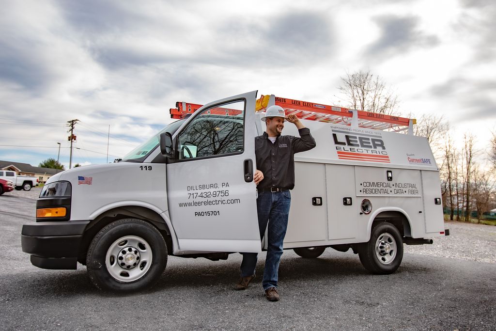 Leer Electric, Inc. electrician standing next to a service vehicle