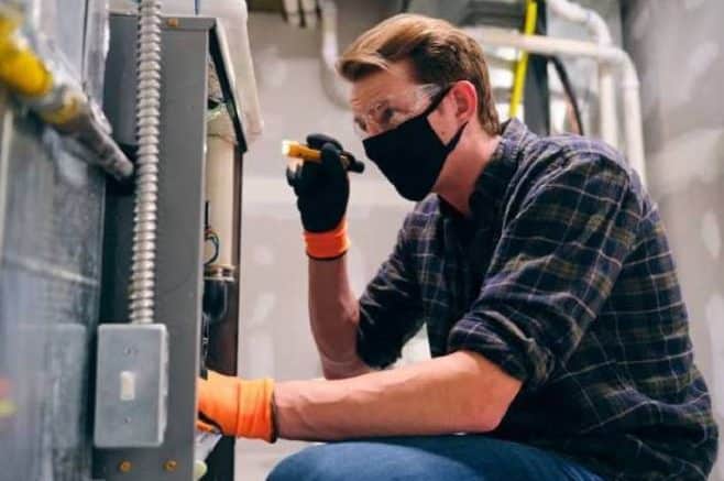 An Electrician With Face Mask Conducting Preventative Maintenance
