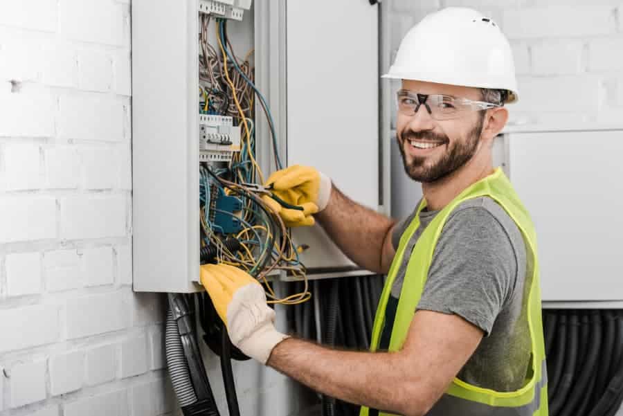 Electrician Repairing Electrical Box With Pliers In Corridor
