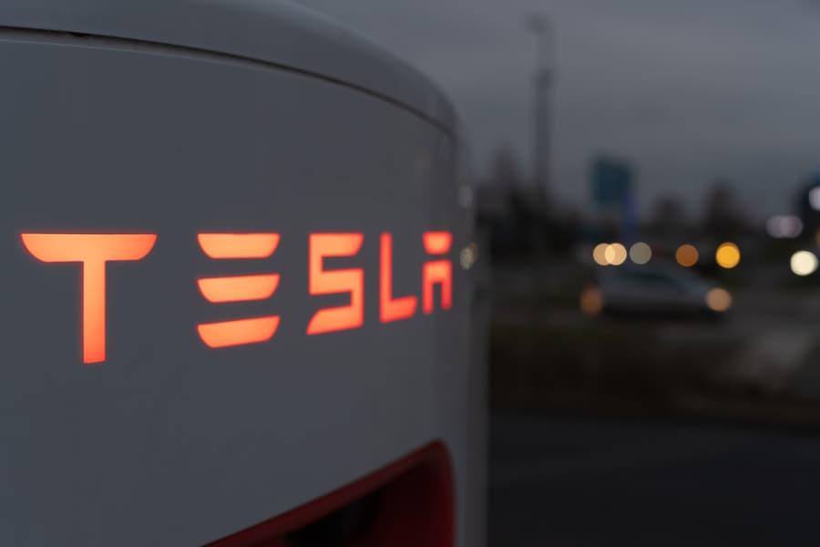 Side angle shot of Tesla supercharger with lit-up letters